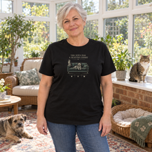 Load image into Gallery viewer, Illustrative lifestyle view of a woman wearing The Sofa Has a Seating Chart pet lover T-shirt in Black in a sunroom with pets.
